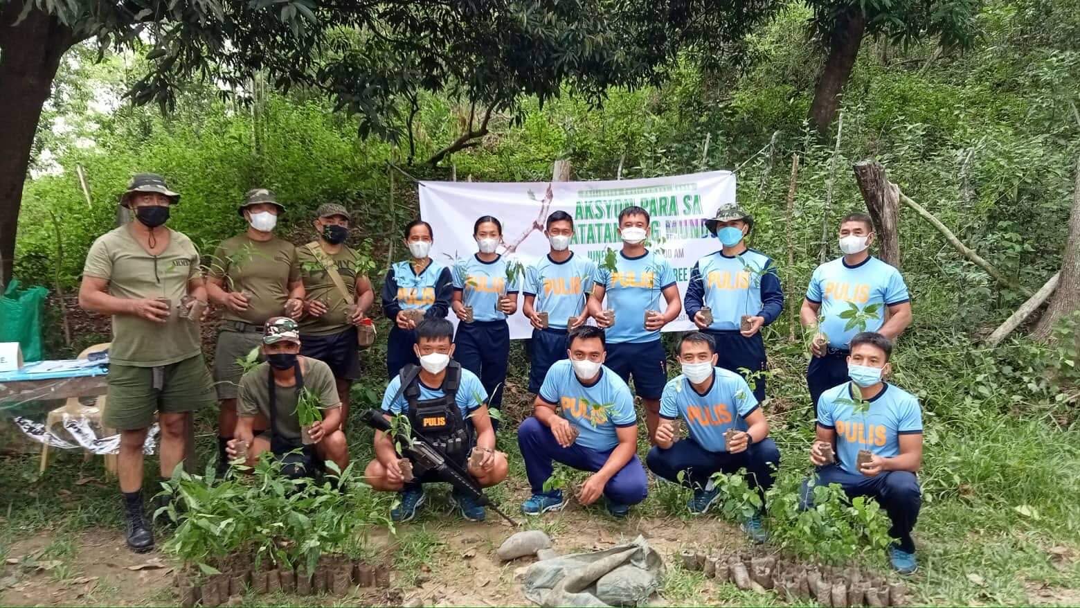 Uniformed personnel holding potted seedlings before a tree planting activity begins
